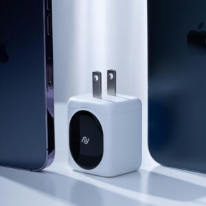 Compact modern charger placed between two dark smartphones, highlighting technology innovation.