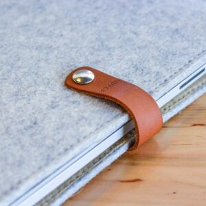 A stylish felt and leather laptop sleeve sits elegantly on a wooden table, offering sleek protection.